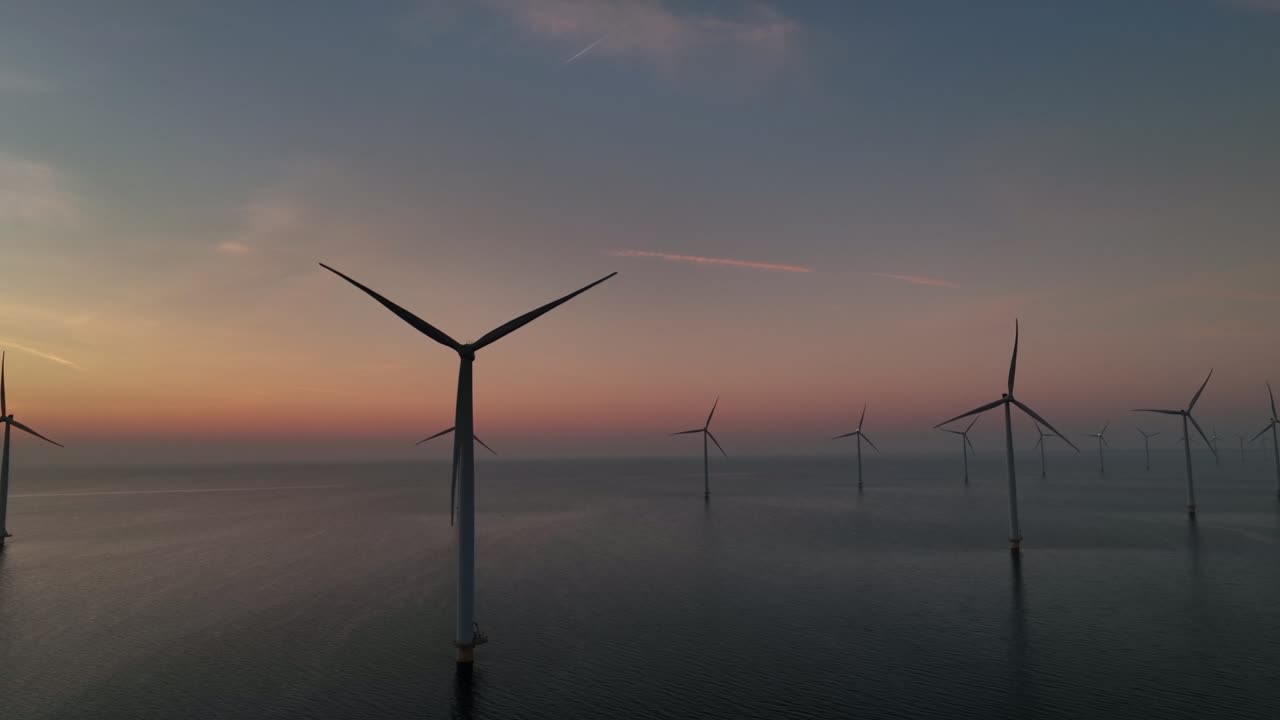 turbinas eólicas que producen energía renovable sostenible en un parque eólico marítimo durante la puesta del sol.