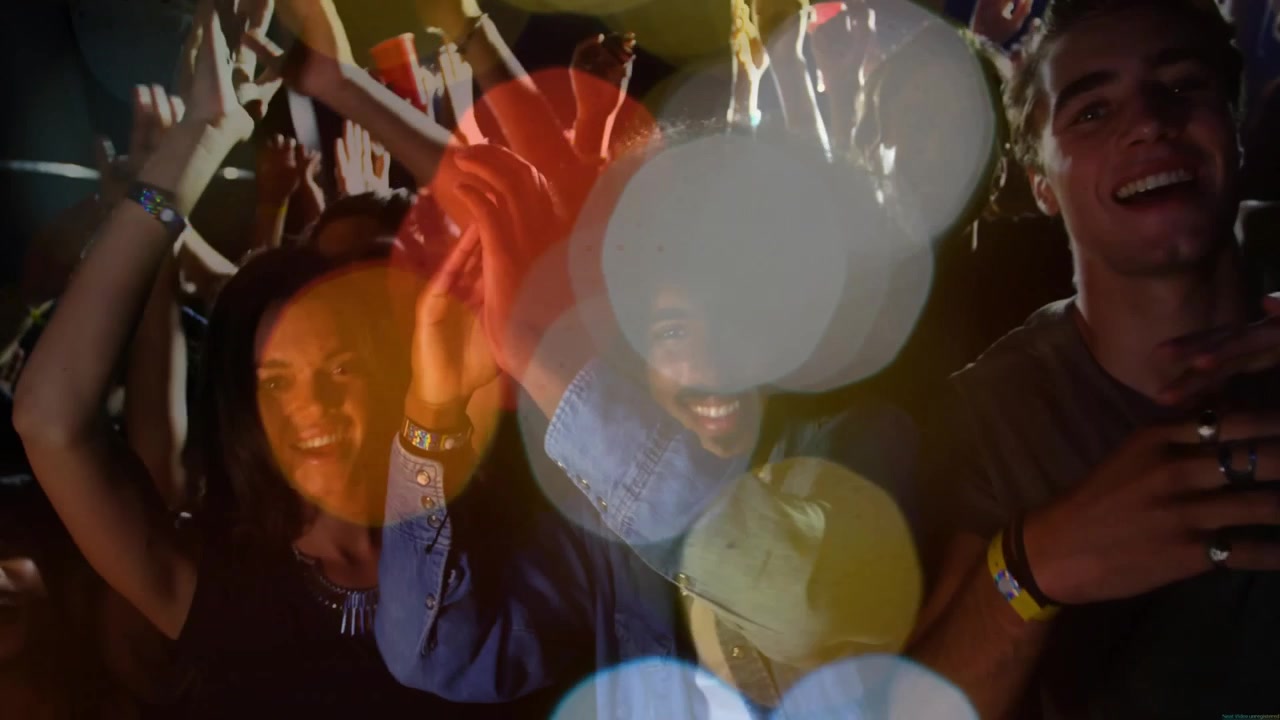 Vertikal video: Tilskuere på første række klapper til livemusik, med lens flare over ansigter og hænder