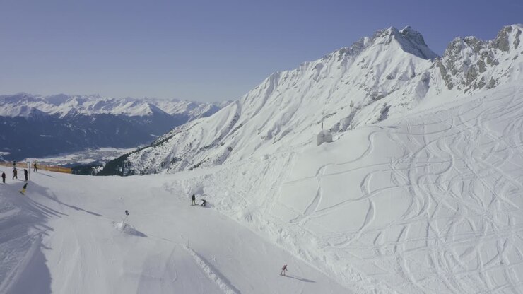 Austrian Alps drone reveal into Nordkette ski resort above Innsbruck, Skyline terrain park skier going off jump at ski resort