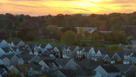 row of suburban homes with gable roofs against a sunset sky