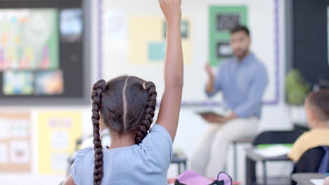 biracial girl raises her hand in a classroom at school