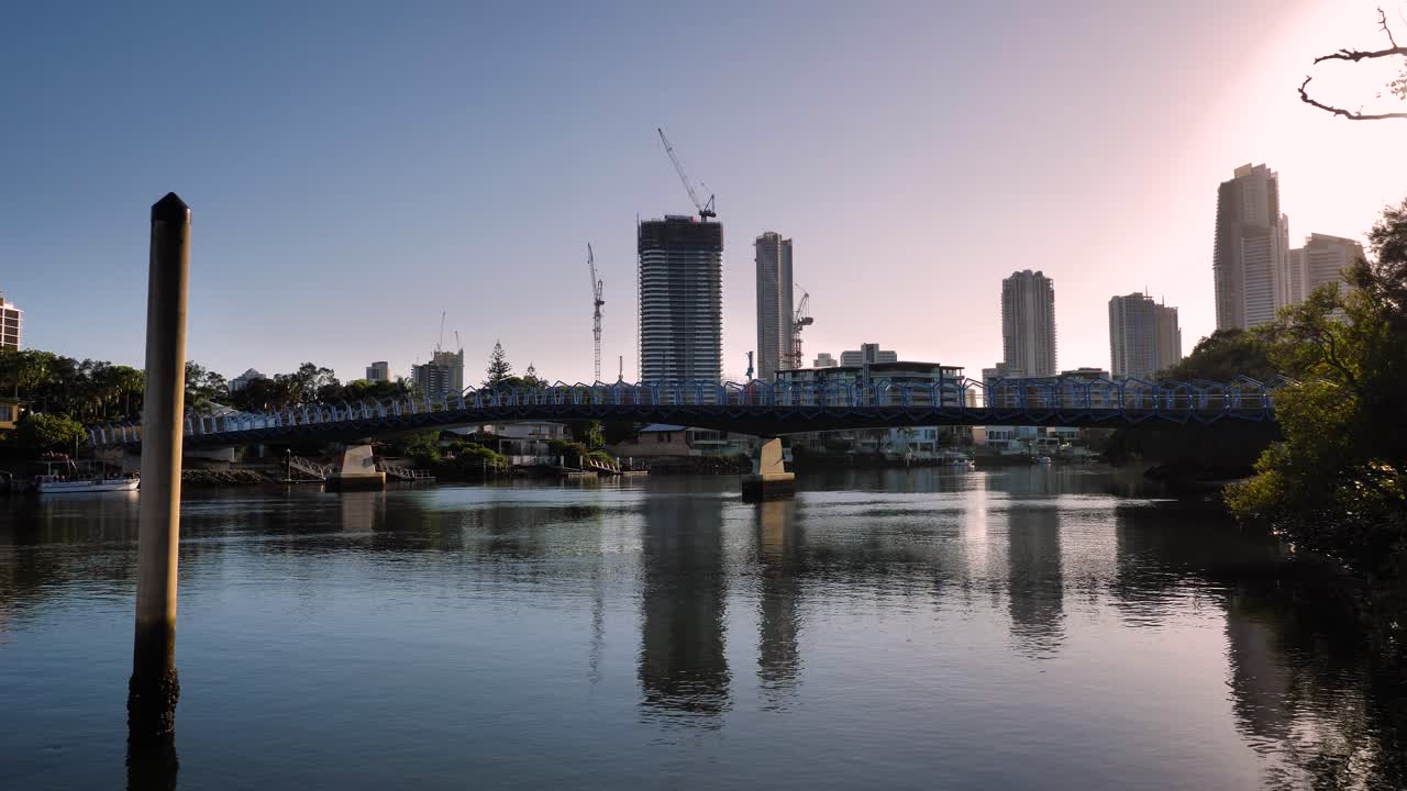 Wide shot of construction cranes behind the Green Bridge on a Gold Coast high-rise apartment building in the morning on a sunny day, Queensland, Australia
