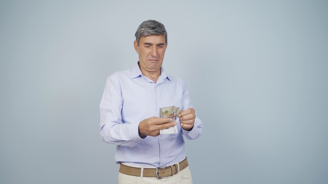 un anciano contando dinero mirando a la cámara.