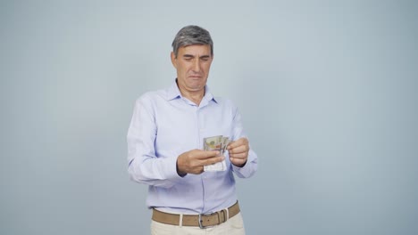 un anciano contando dinero mirando a la cámara.