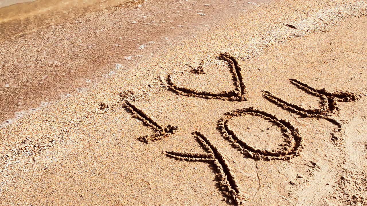 Iscrizione Ti amo sulla sabbia. Riprese sulla spiaggia