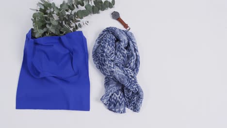 video of blue canvas bag with plant, scarf, watch, copy space on white background