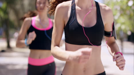 Close-up-crop-of-torso-of-Two-running-women-Fitness-athletic-friends-jogging-in-the-urban-city