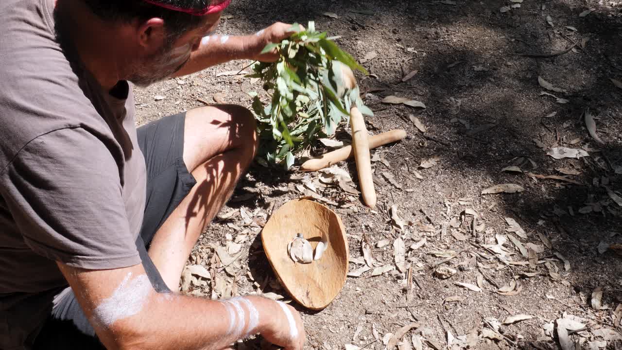 Australian Aboriginal Smoking Ceremony, man creates smoke on a traditional wooden bowl as part of an ancient indigenous custom