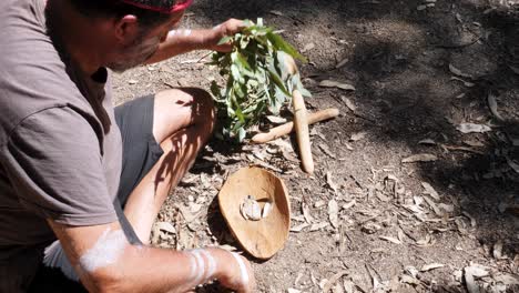 ceremonia de fumar aborigen australiano, el hombre crea humo en un cuenco de madera tradicional como parte de una antigua costumbre indígena