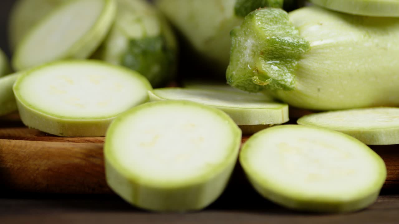 나무 절단판에 둥근 zucchini 조각을 천천히 회전합니다.