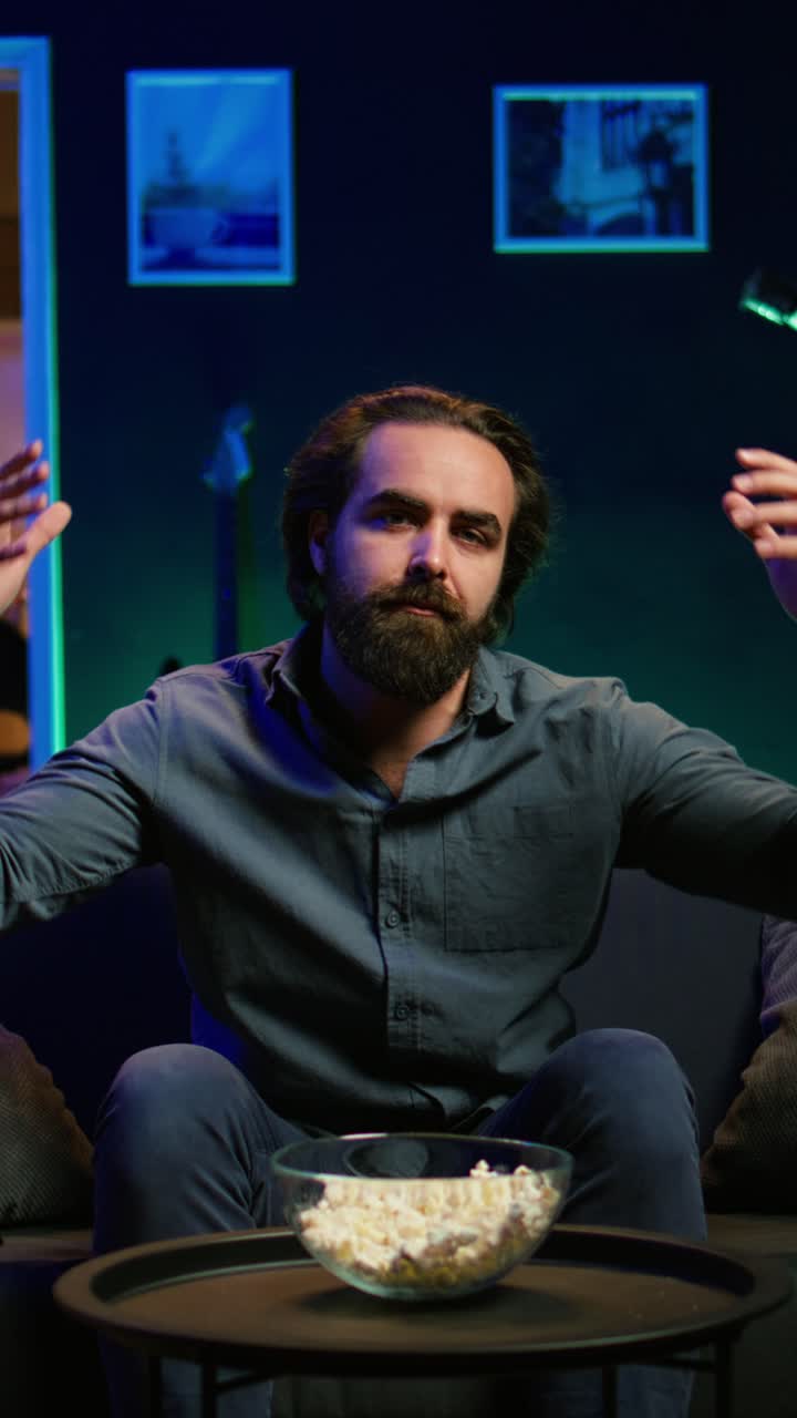 Vertical video Dejected man at home on couch watching sports match on live broadcast