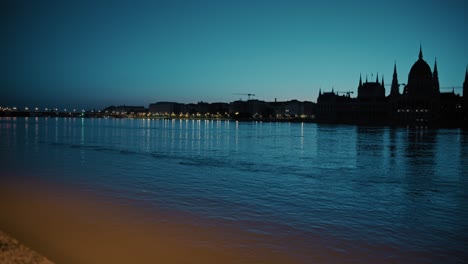 night view of the danube river with city lights reflecting and the silhouette of the hungarian parliament building