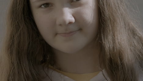 closeup portrait of a cute girl with brown hair looking up at camera and then back down