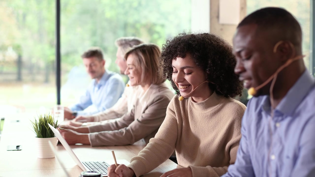 Diverse Call Center Agents Working on Laptops with Headsets in Modern Office