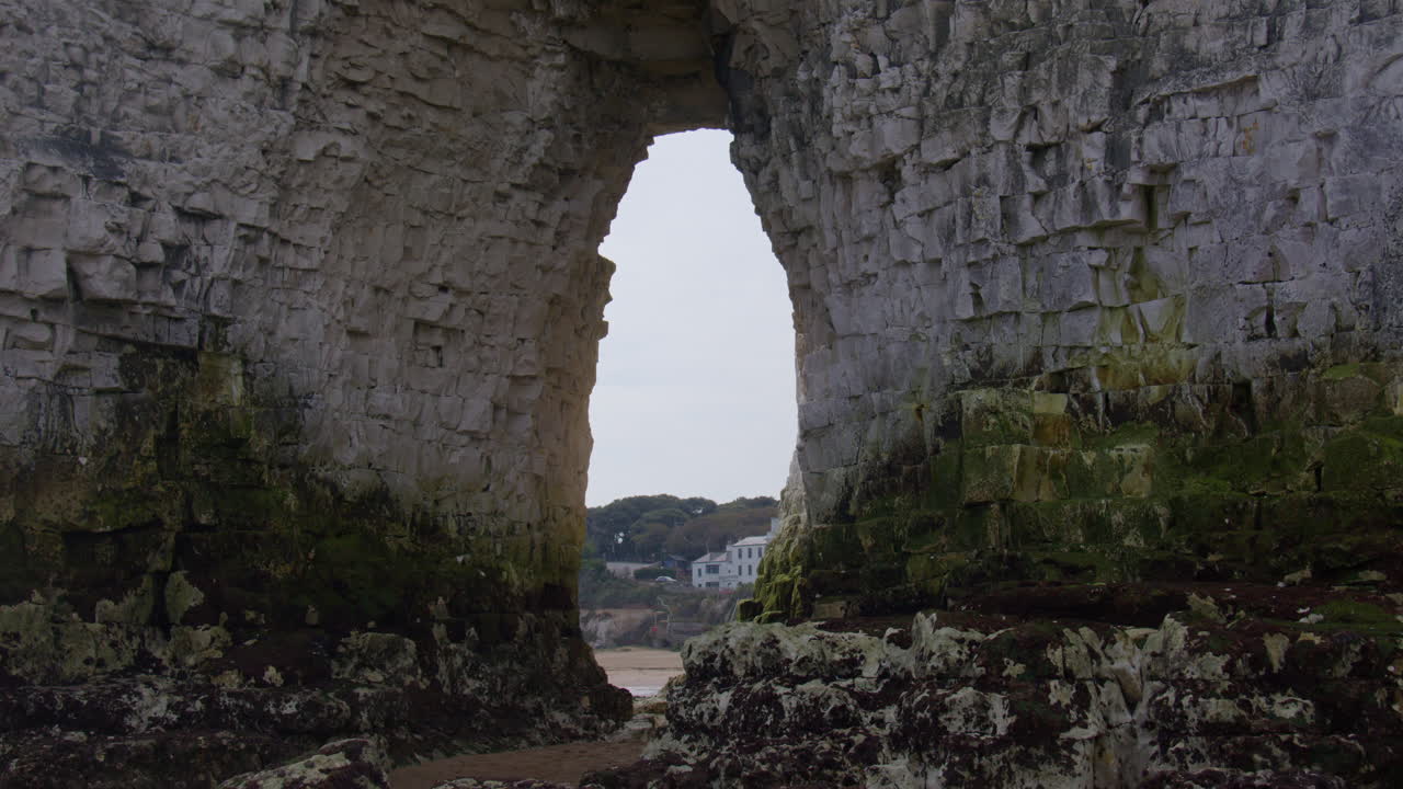Ampia inquadratura del faraglione calcareo Kingsgate Arch con la baia di Kingsgate sullo sfondo