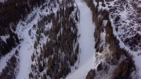 Flying-over-frozen-mountain-river-in-Canadian-Prairies-and-winter-forest