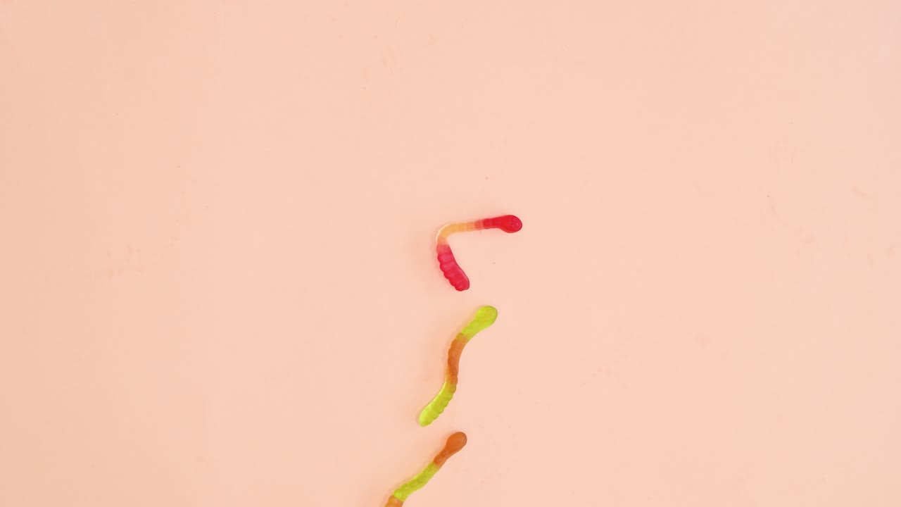 творческая анимация с остановкой движения различных красочных конфет и леденцов, меняющихся на ярком пастельно-оранжевом фоне.