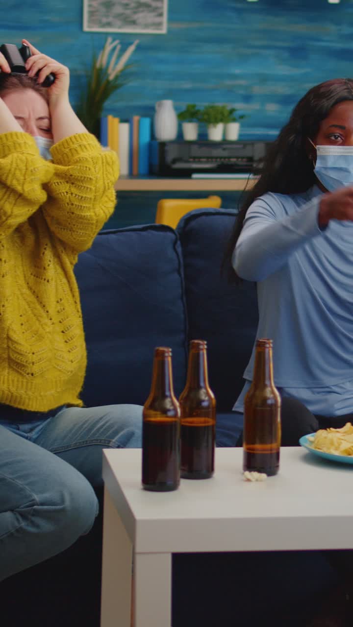 Vertical video: Mixed race women with protection mask playing video game