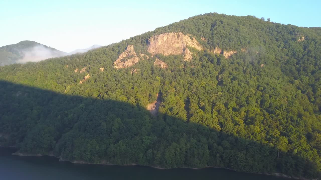 la luz del sol brilla sobre la roca de la ladera en la orilla del lago tarnita