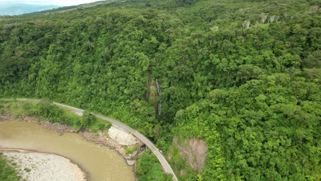 cascada a la orilla de carretera rodeada de bosque y montañas