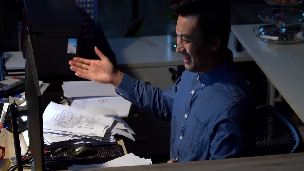 Happy attractive businessman finishing to work at office late at night with celebration for completion. Excited man or employee working late with smile in success on project deadline, documents
