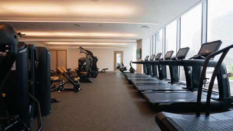 pushing into a well-equipped fitness center, highlighting cable machines and a row of treadmills for various workout options