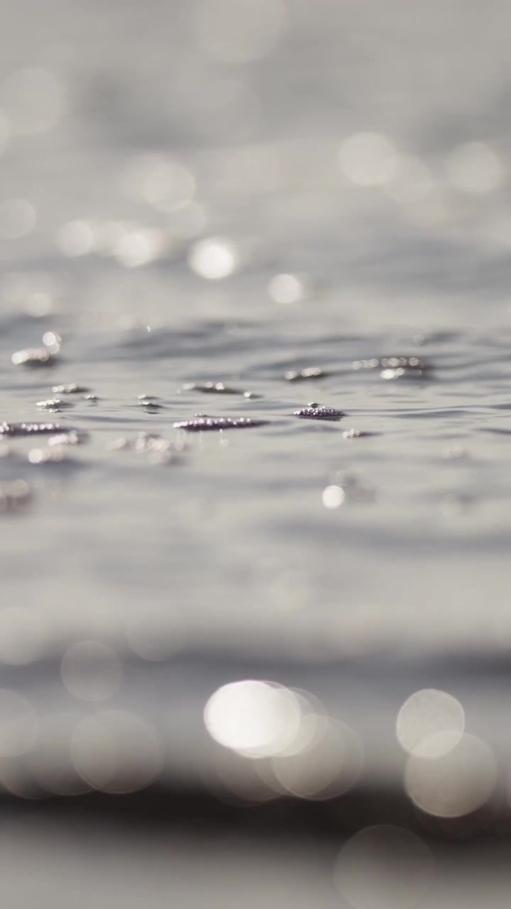 Il sole proietta riflessi luminosi su una superficie d'acqua calma, creando un'atmosfera serena e riflessiva. Adatto per l'uso in progetti video meditativi o rilassanti.
