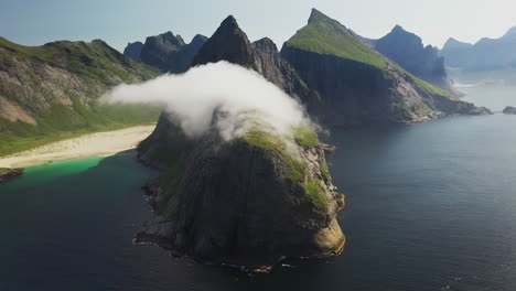 Toma-Cinematográfica-De-Un-Dron-Giratorio-De-Nubes-Moviéndose-Sobre-Acantilados-En-La-Playa-De-Horseid-Con-Agua-Azul-Turquesa