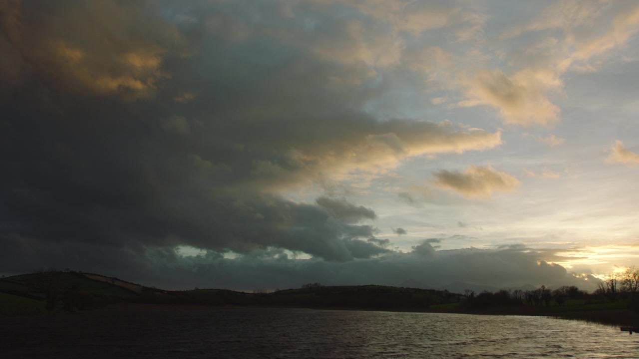 Hermosas nubes azules y amarillas sobre un lago con tonos rosados y amarillos.