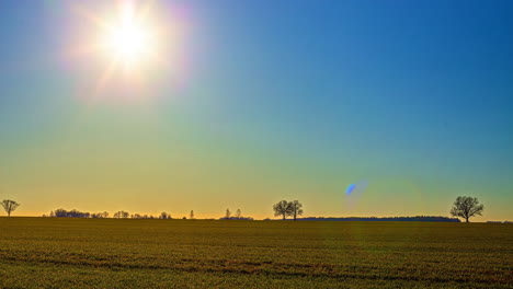 Zeitraffer-Eines-Leuchtenden-Sonnenaufgangs,-Der-An-Einem-Frühlingsabend-über-Ländliches-Ackerland-Zieht