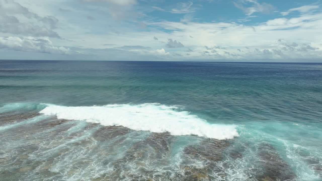 Aerial high angle approach to ocean waves crashing and curling on fringing reef