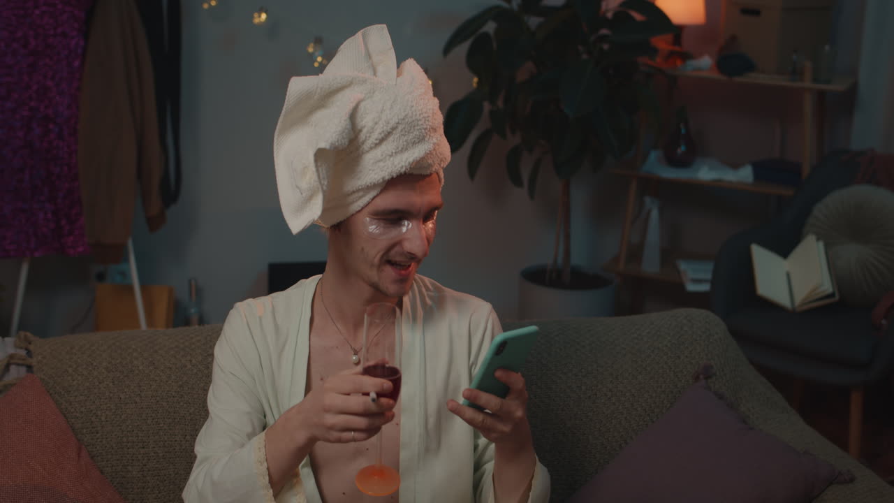 Uomo in accappatoio che si fa un selfie con del vino