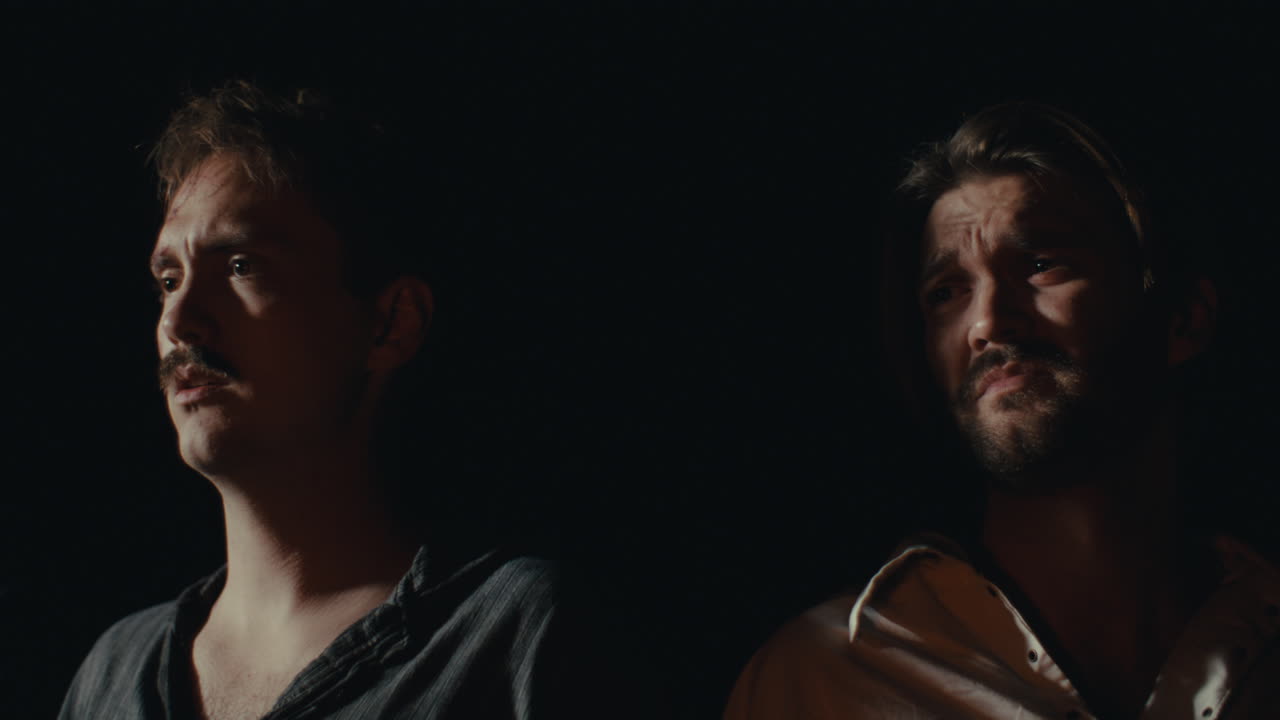 Two Men in Low Light with Focused Expressions