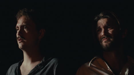 two men in low light with focused expressions