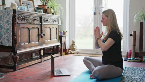 a woman doing yoga while watching her laptop