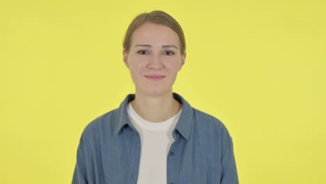 mujer joven apuntando a la cámara en fondo amarillo