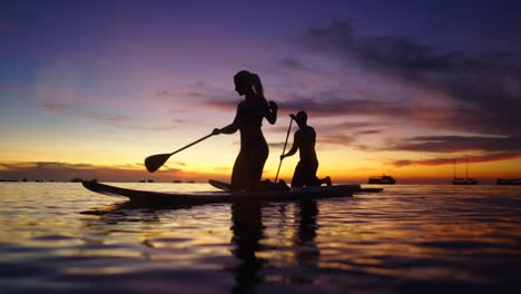 couple paddleboarding on the ocean at sunset
