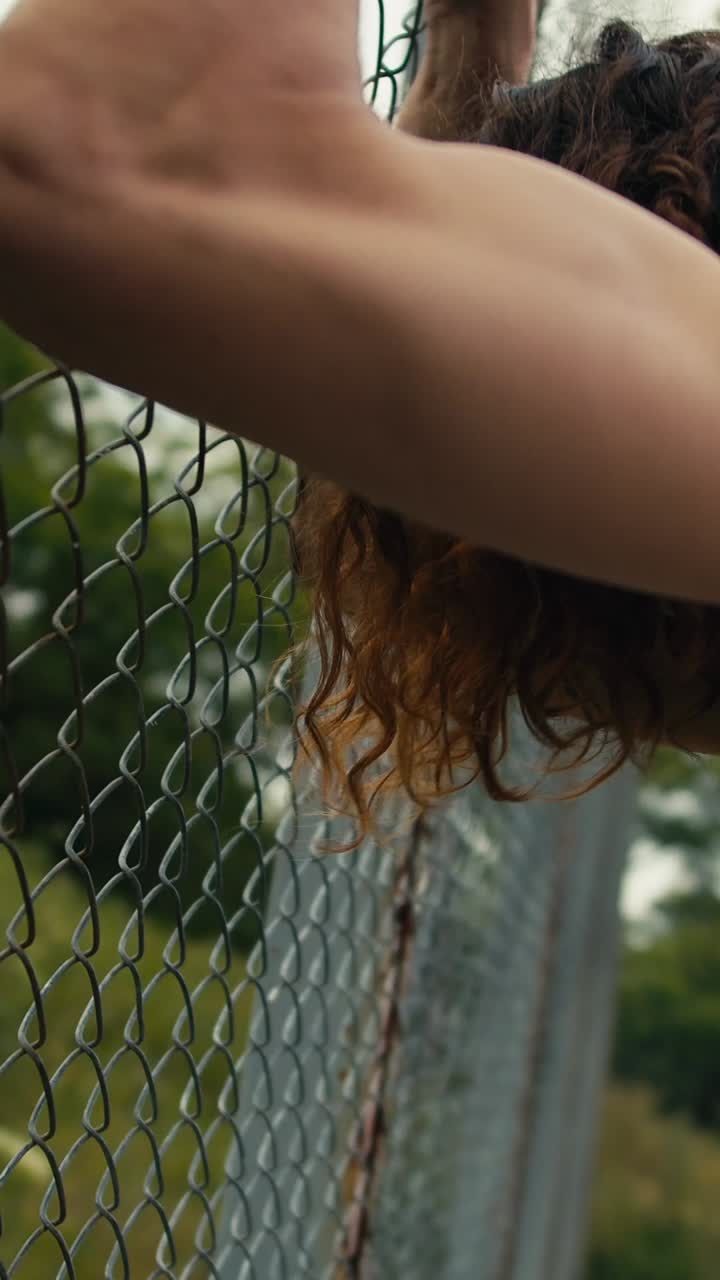 Man exercising outdoors near a chain link fence