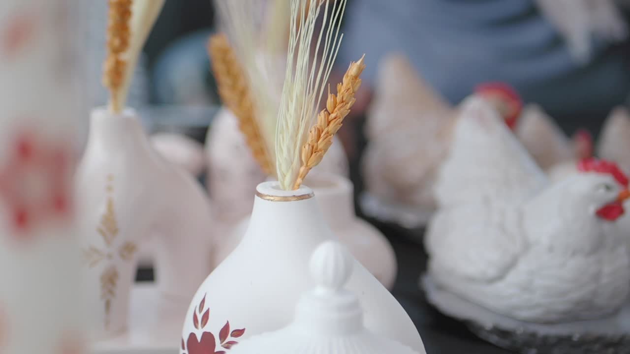 primer plano de un jarrón de cerámica blanca con trigo y otras decoraciones