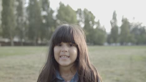 retrato de una linda chica latina parada en el parque, sonriendo a la cámara y saltando