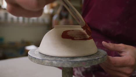 Vista-De-Cerca-De-Una-Alfarera-Con-Delantal-Pintando-Una-Olla-En-La-Rueda-De-Alfarero-En-El-Estudio-De-Cerámica