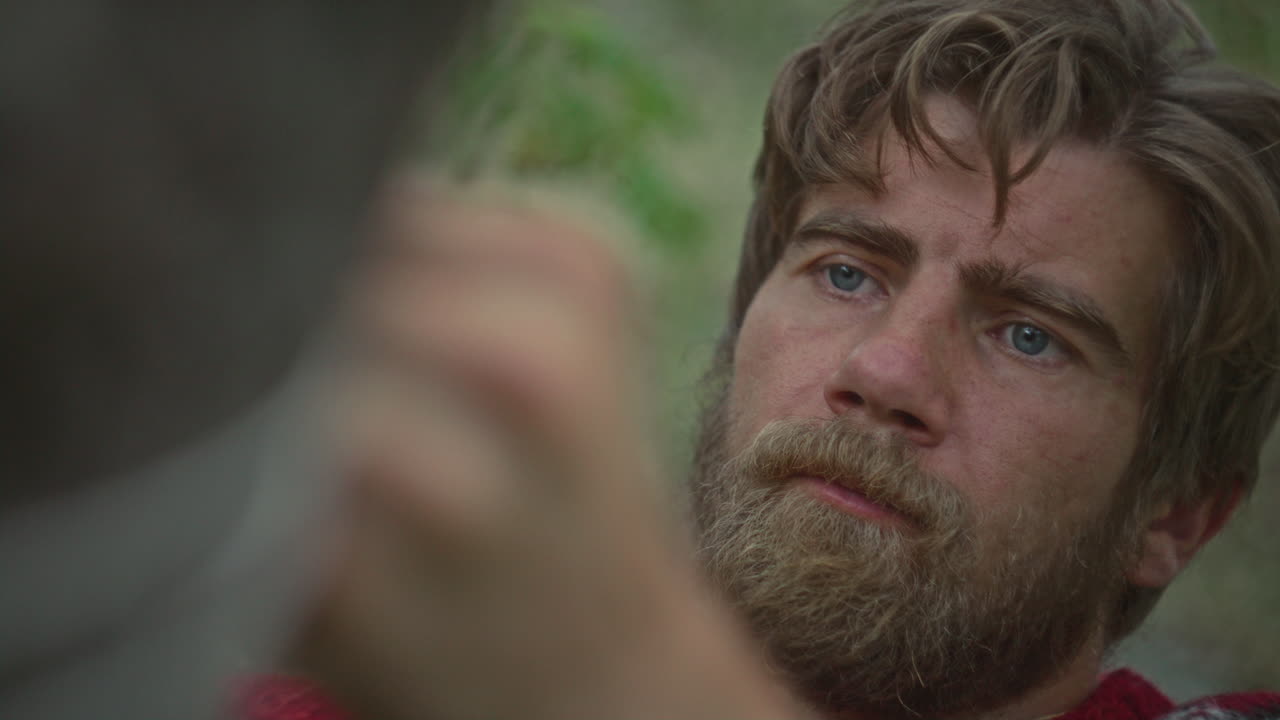 Man Tying Rope around Tree to Set Up Camping Tent in Woods