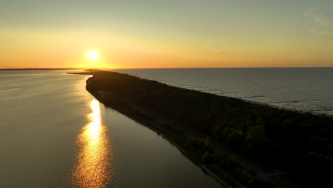 fotografía aérea de kuźnica, polonia, que muestra una hermosa puesta de sol sobre la costa con el sol proyectando un largo reflejo en el agua