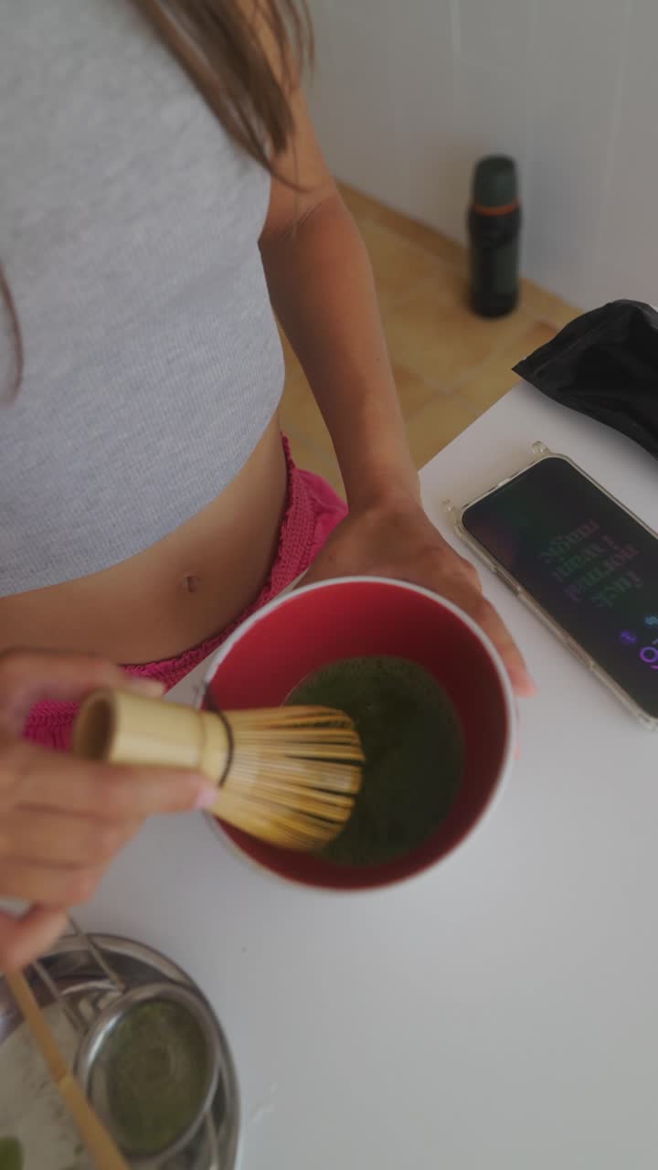 Person preparing matcha tea with a whisk