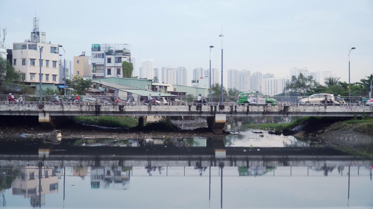 Old Bridge Across Polluted River with Motorbikes and Reflection in the Water
