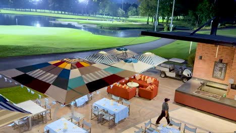 man walks past outdoor seating and umbrellas