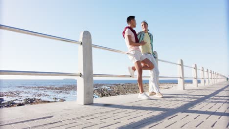 happy diverse gay male couple talking at promenade by the sea, slow motion