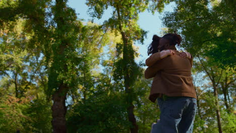 Happy-father-spinning-daughter-hugging-little-kid.-Family-playing-in-sunny-park.