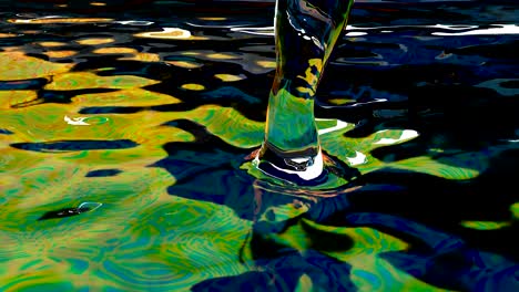 jet of liquid falls into an oily liquid super slow motion macro rainbow water splash macro shot. 1000fps 4k