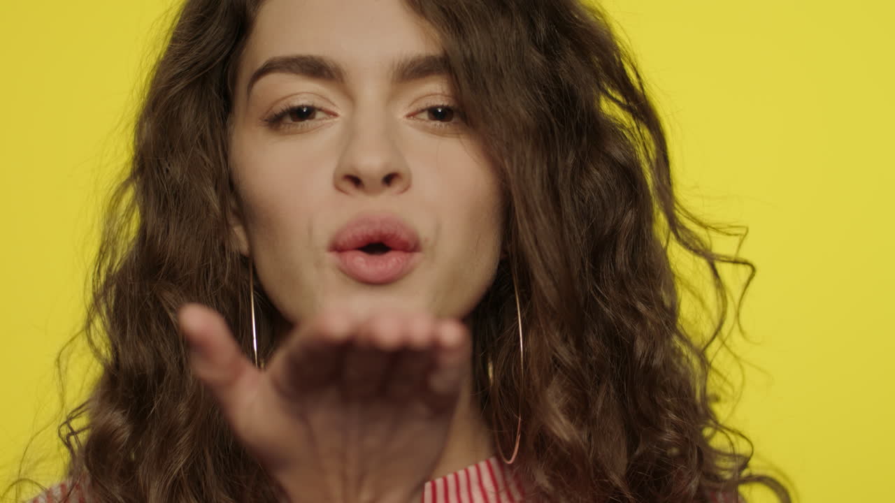 mujer joven beso de aire. chica bonita soplando beso de aire de la mano a la cámara